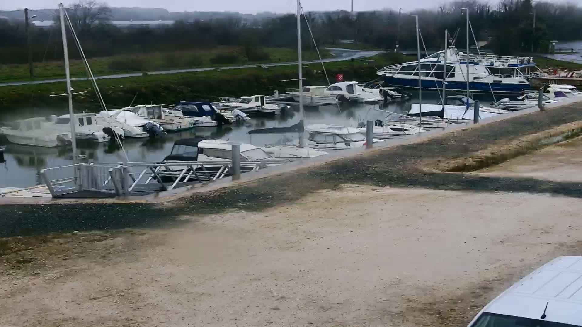 Many boats are docked at a marina on an overcast day.