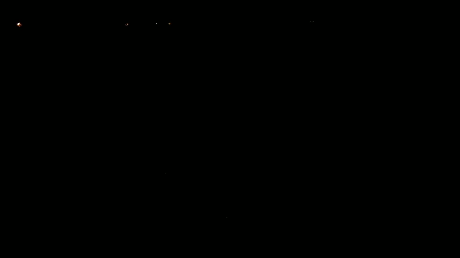 The image shows a dark night scene with a few distant, faint lights.