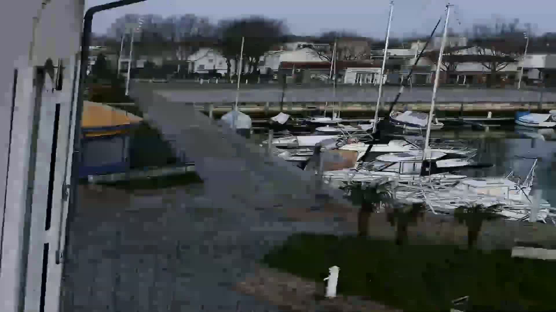 A marina filled with numerous boats and yachts is viewed from a slightly elevated position on an overcast day.