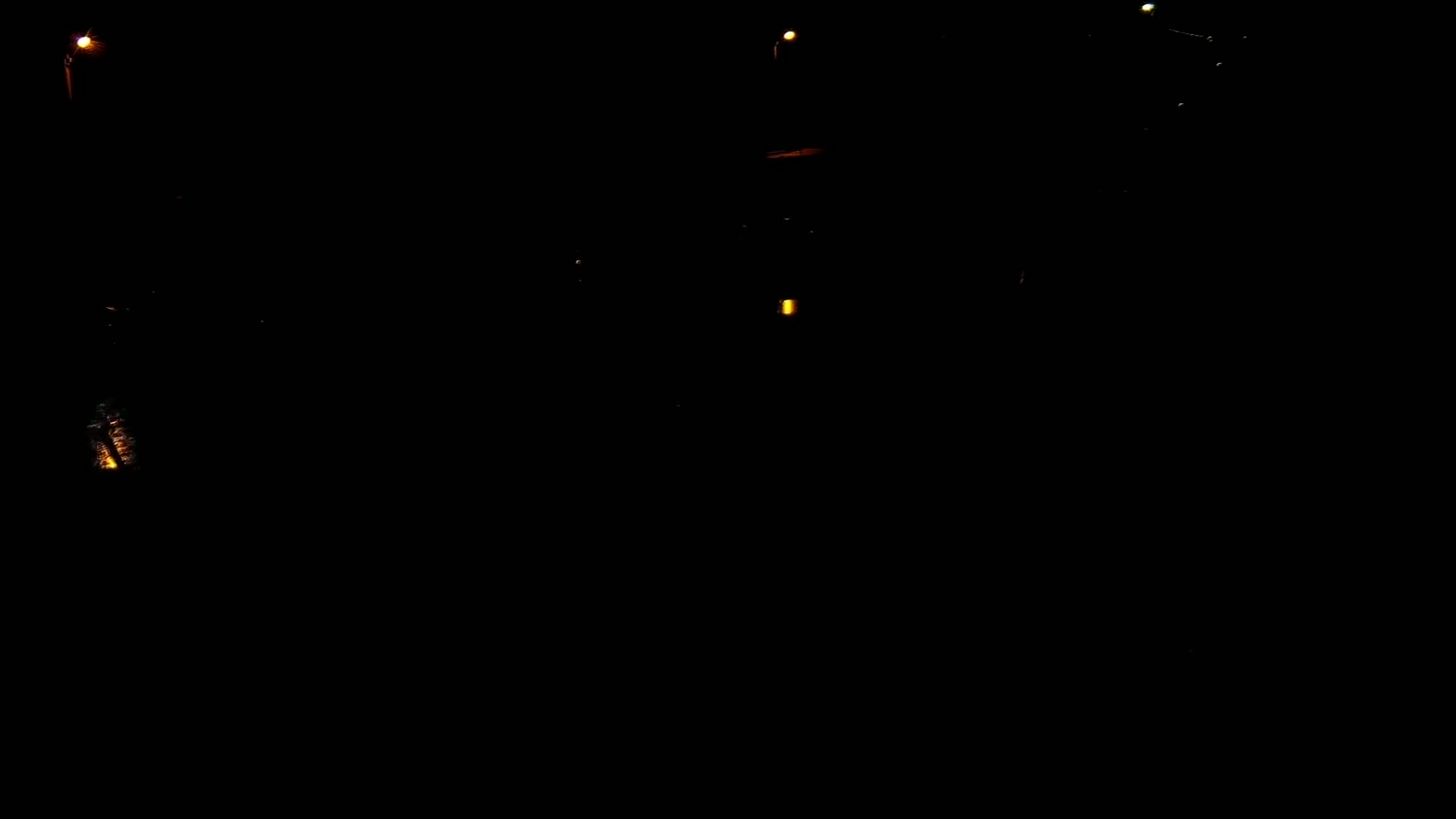 A dark nighttime scene shows several dim, distant lights.
