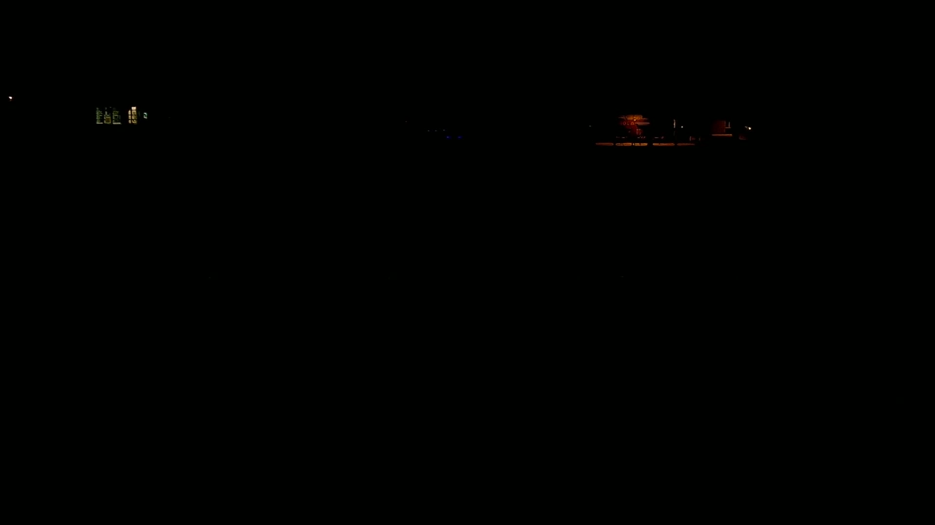At night, dimly lit houses are visible in the distance.