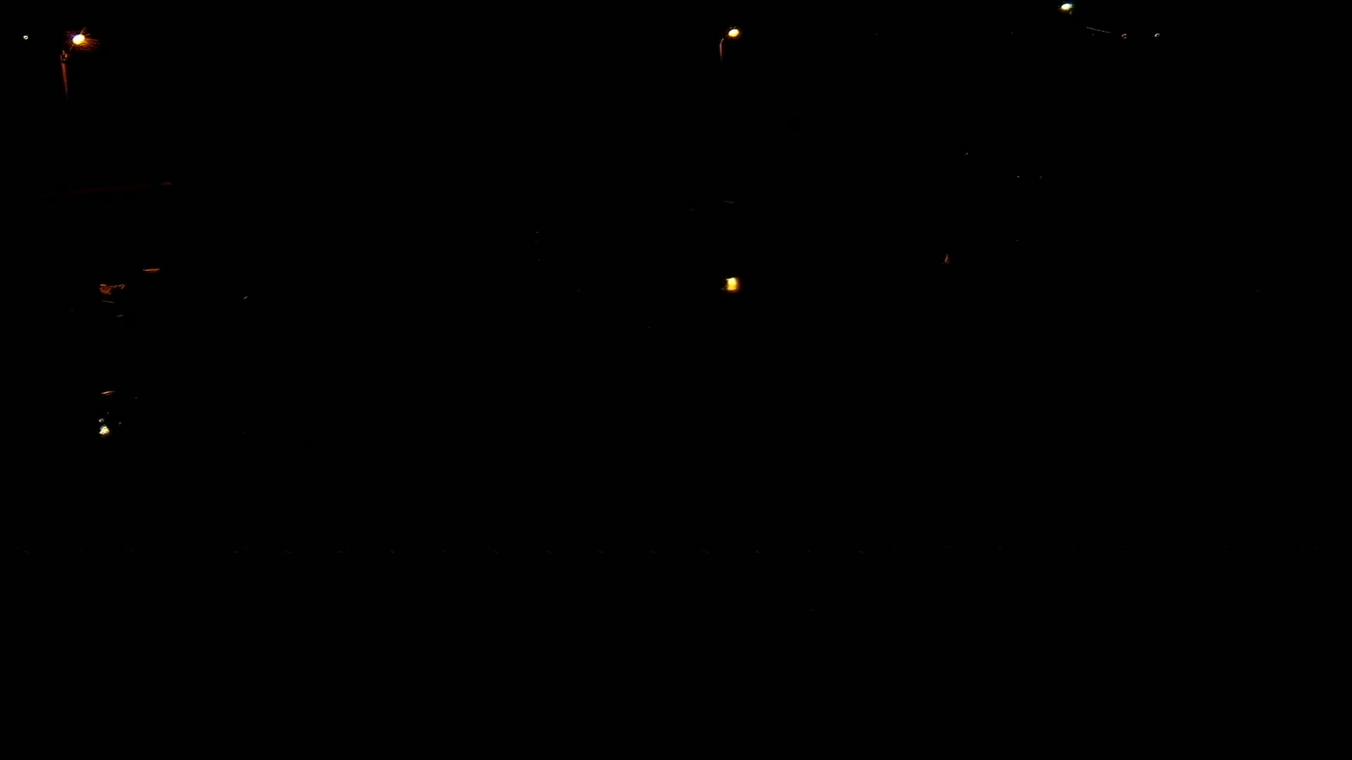 A dark scene at night is illuminated by several small, distant lights.