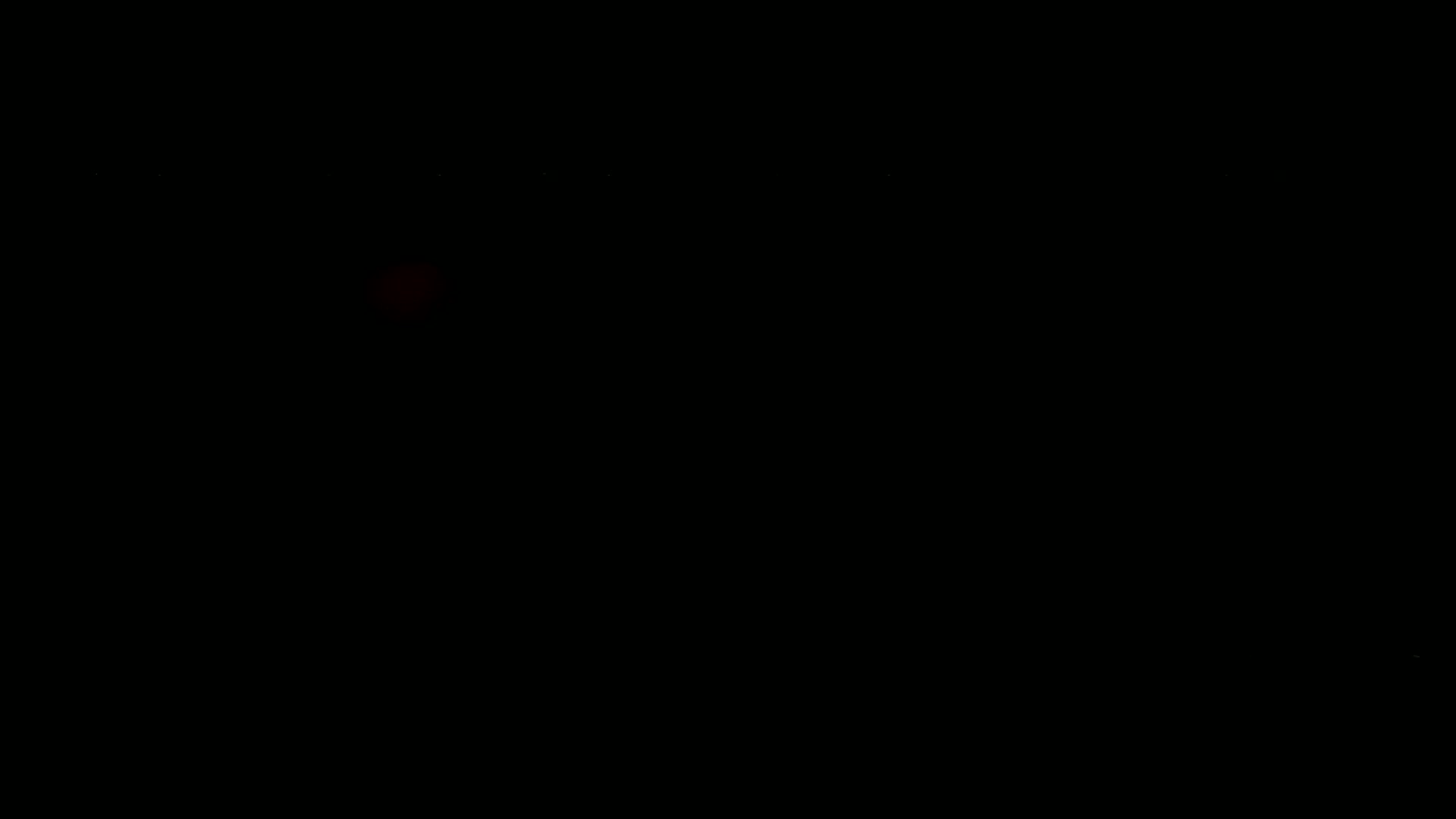 A faint, blurry red light is visible in an otherwise completely dark environment.