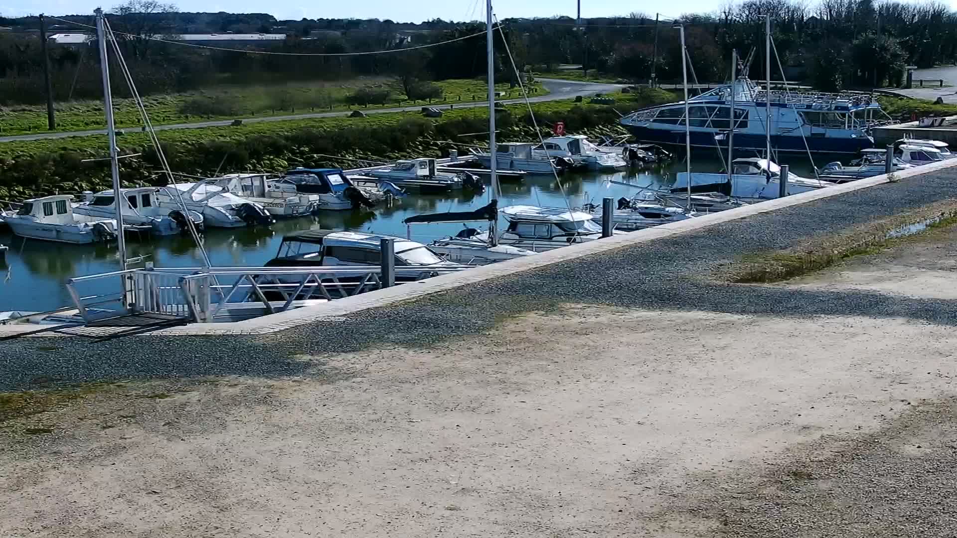 Many motorboats and sailboats are docked at a marina on a sunny day.