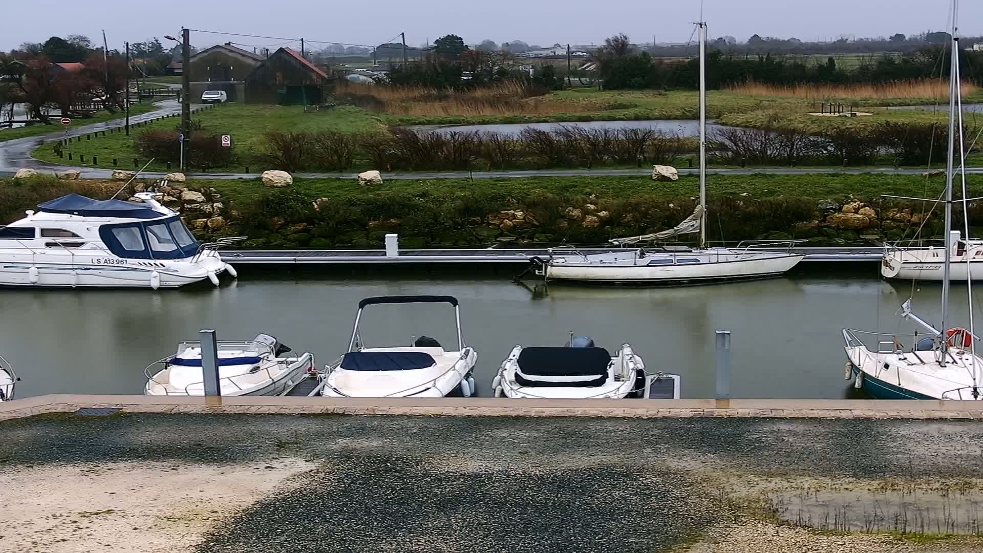 Several motorboats and sailboats are moored at a dock on an overcast day.