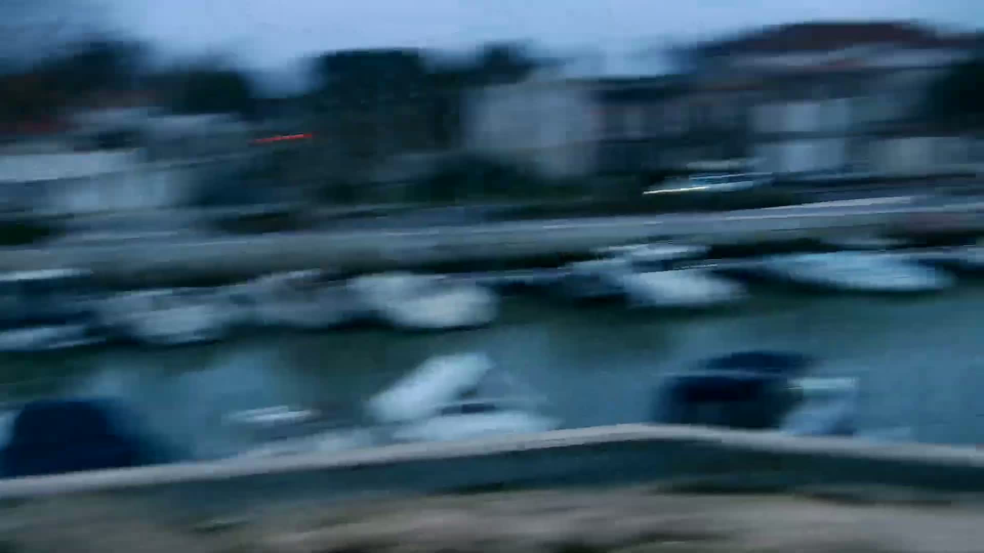 A blurry image shows a marina filled with boats under a dusky sky.