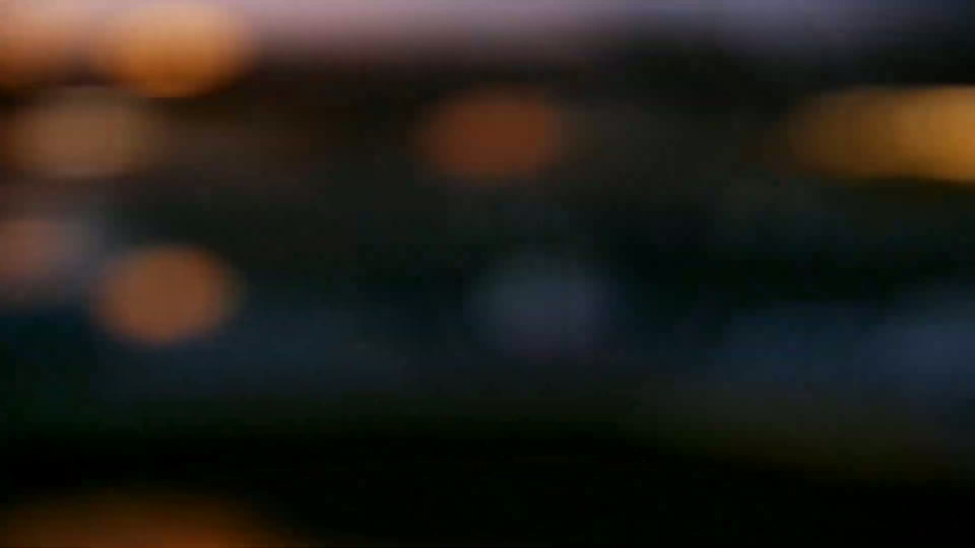 A blurry out-of-focus image shows dark colors and muted orange and blue bokeh lights.