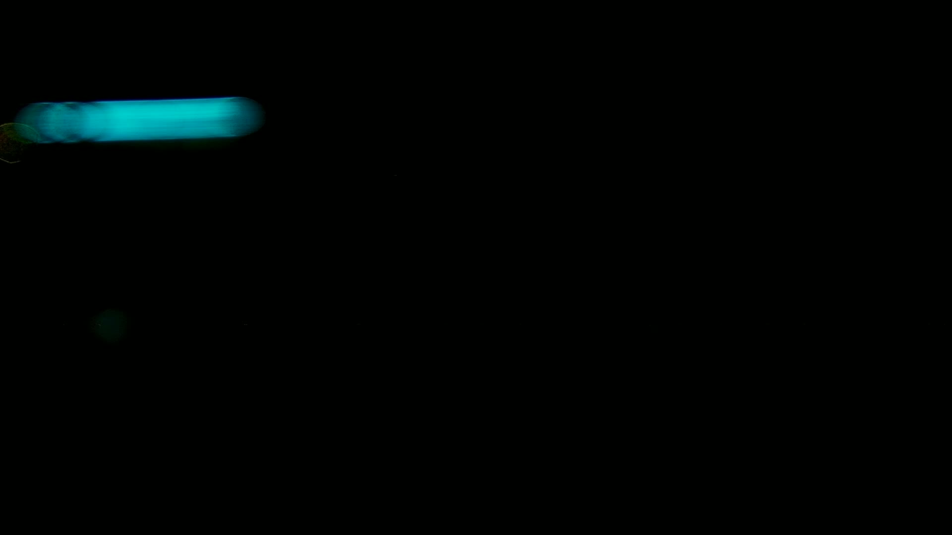 A blurry, teal light streaks across a completely black background.
