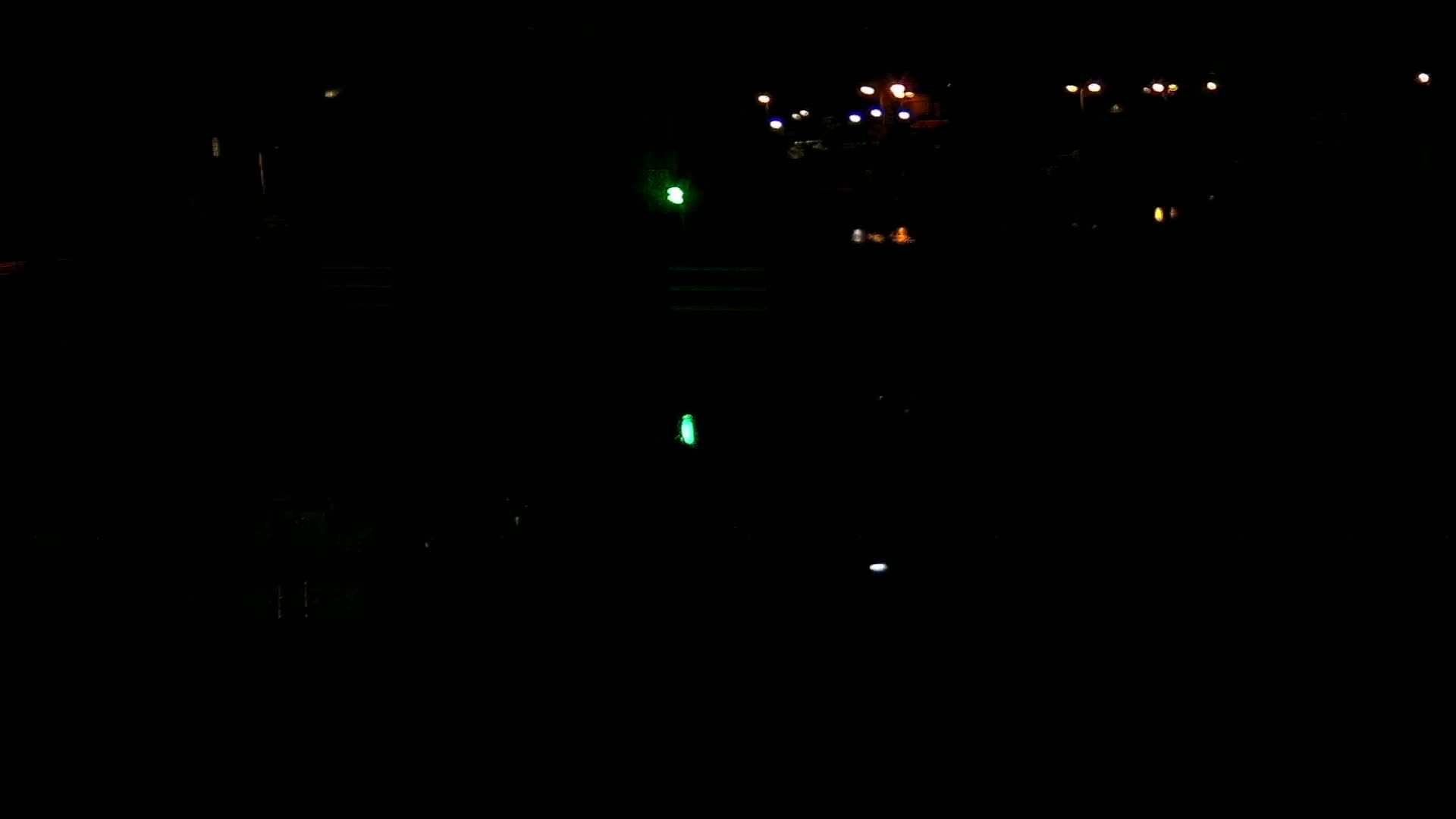 A dark nighttime scene shows several distant lights and a few faint lights closer to the viewer.