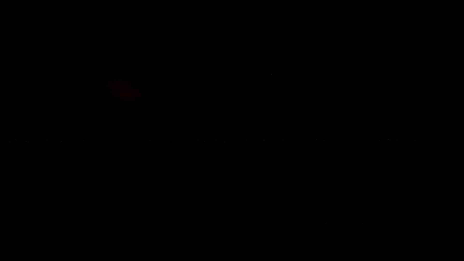 A dark image shows a faint reddish glow in the distance against a mostly black background.