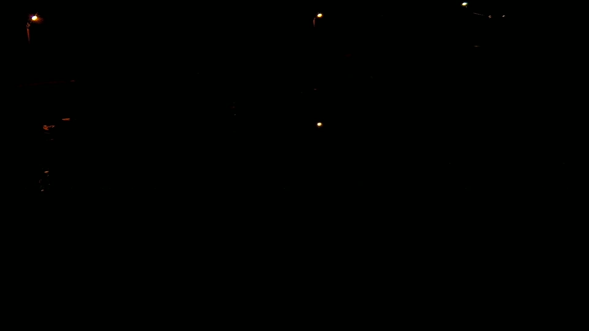 A very dark scene is illuminated by a few small, distant lights.