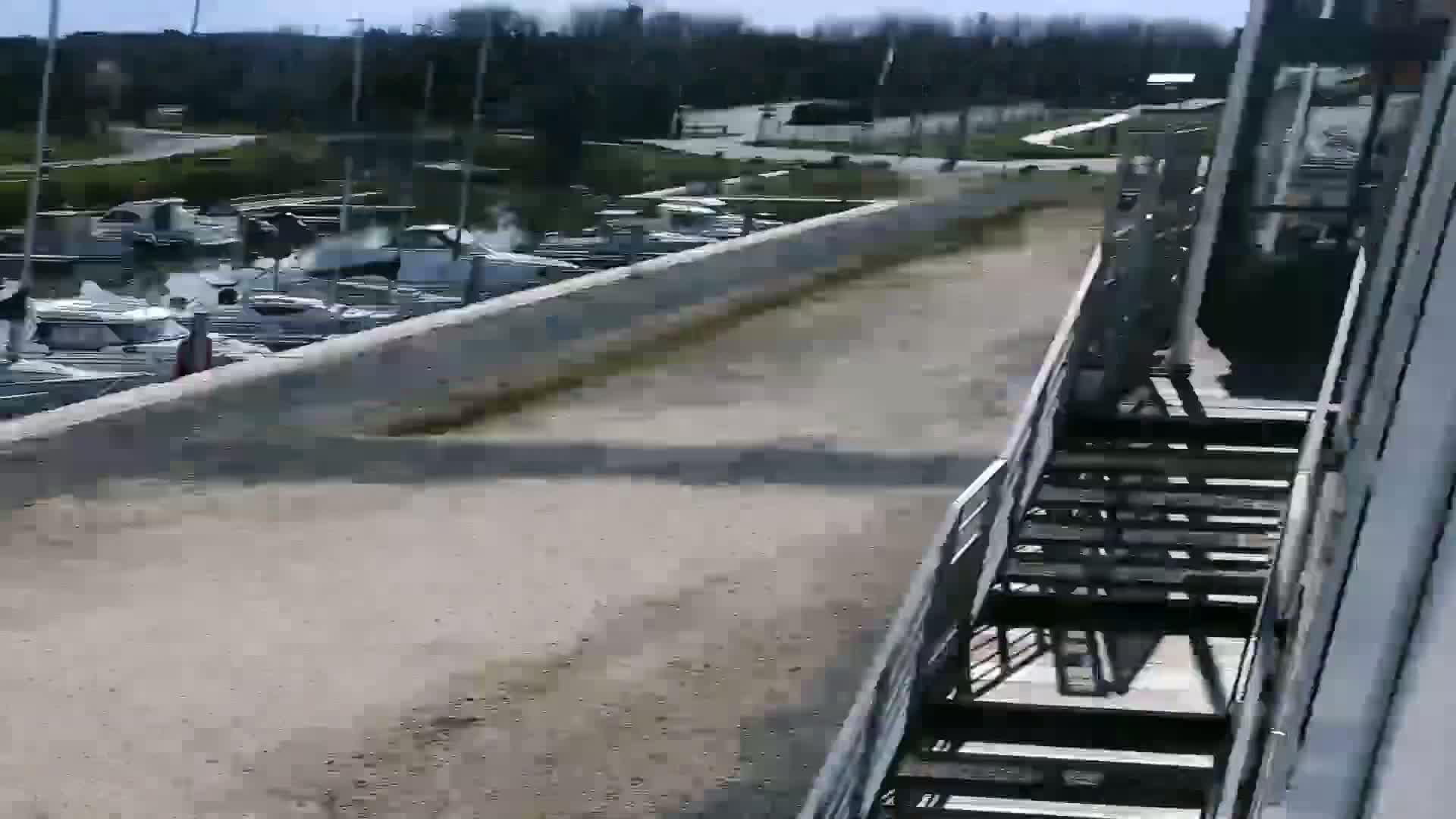 A paved walkway overlooks a marina filled with numerous boats on a sunny day.