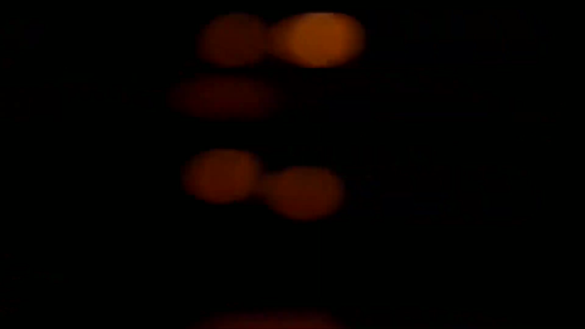 Several blurry, amber-colored lights are visible against a completely dark background.