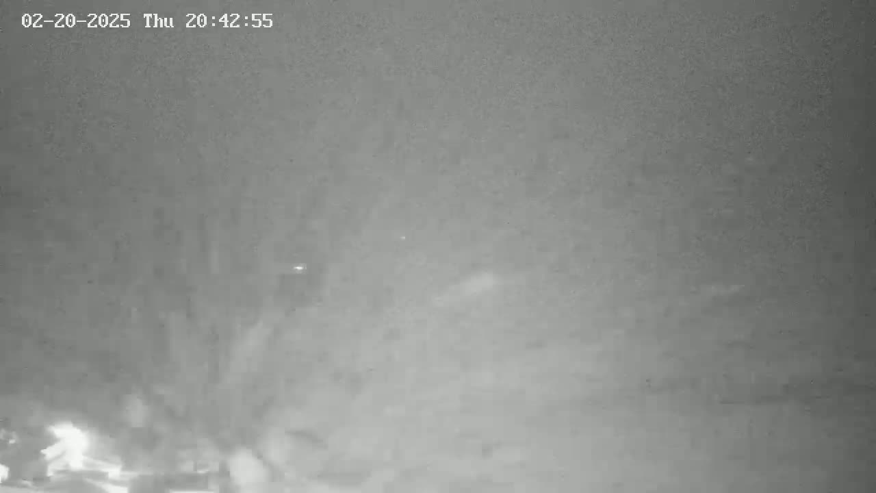 A grainy, low-light image shows a blurry, indistinct scene at night, possibly obscured by fog or mist.