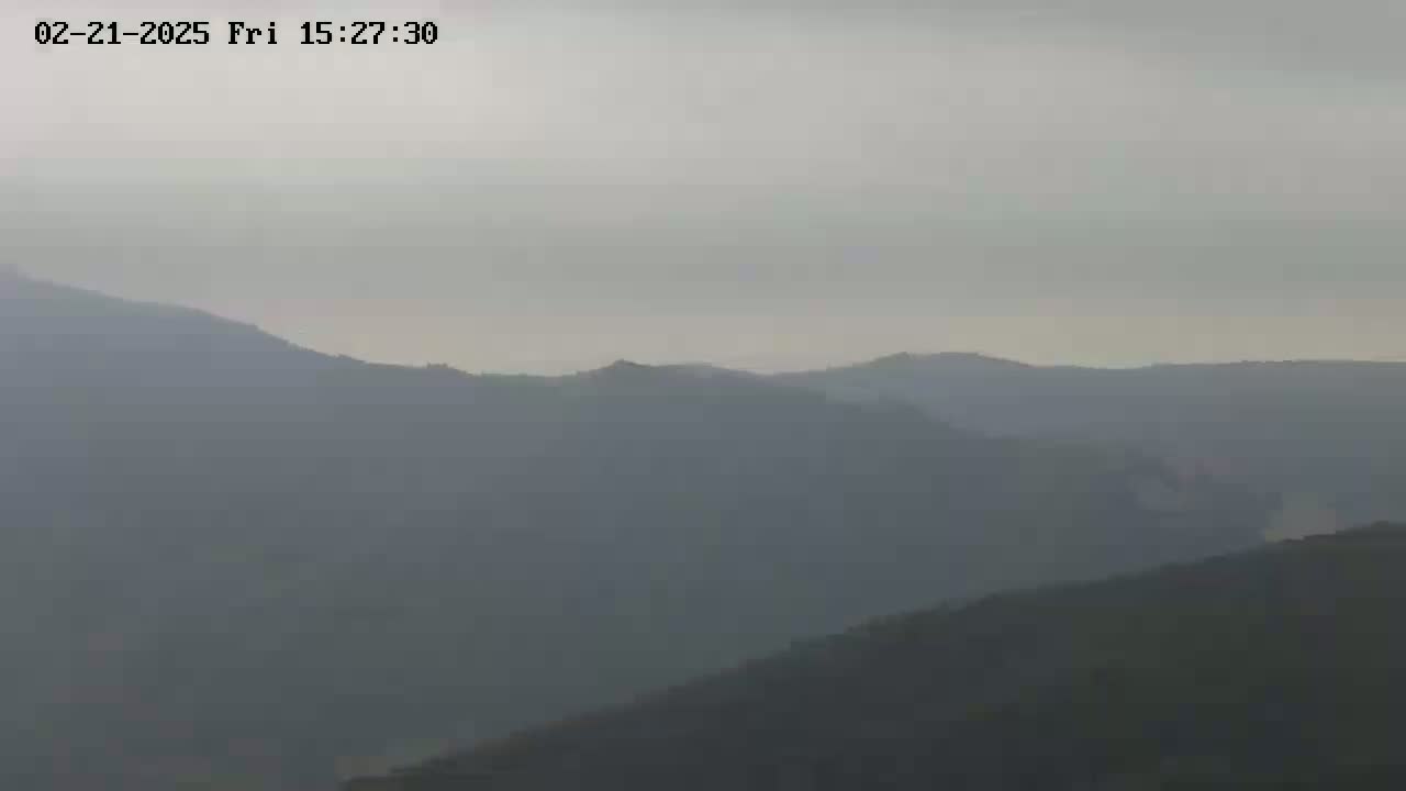 A hazy, overcast sky hangs over a range of indistinct, dark-colored mountains.