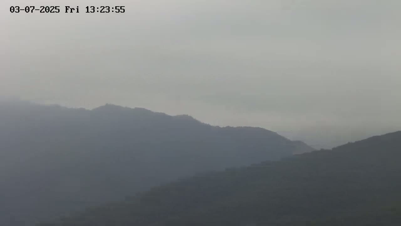 A hazy view of distant, dark mountains under a gray, overcast sky.