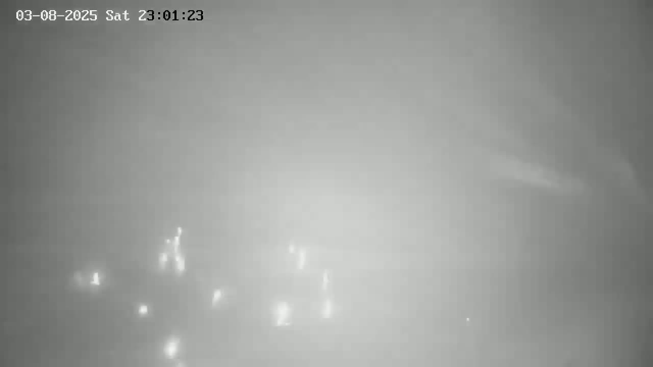 Faint lights are visible through a thick fog at night.