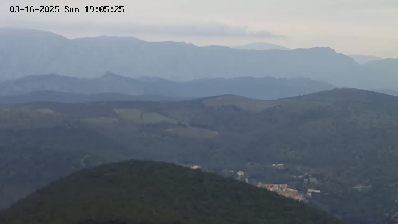 A hazy view shows rolling hills and distant mountains under an overcast sky.