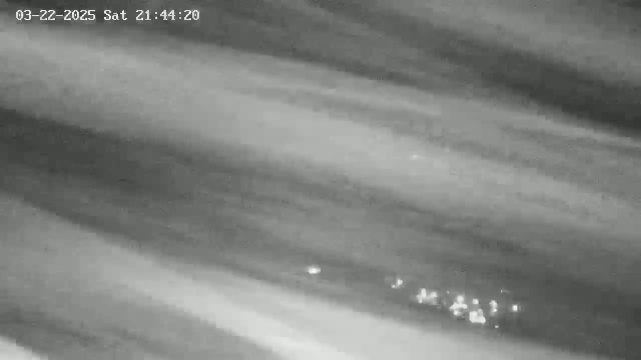 A grayscale image shows a cloudy, possibly nighttime sky with faint streaks of light.