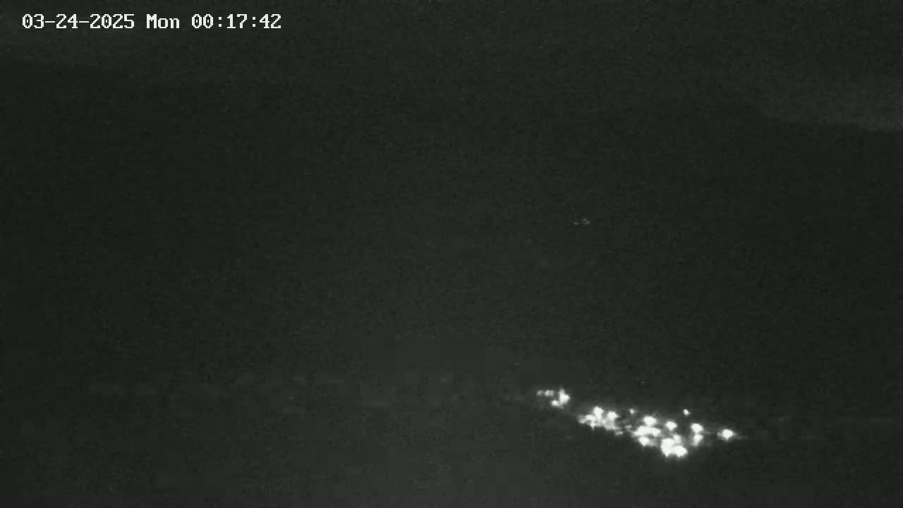 A long line of faint lights is visible in the distance on a dark, nighttime landscape.