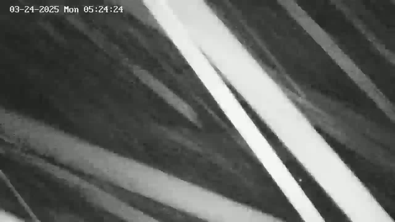 A blurry, grayscale image shows diagonal streaks of light and dark, suggesting motion blur.