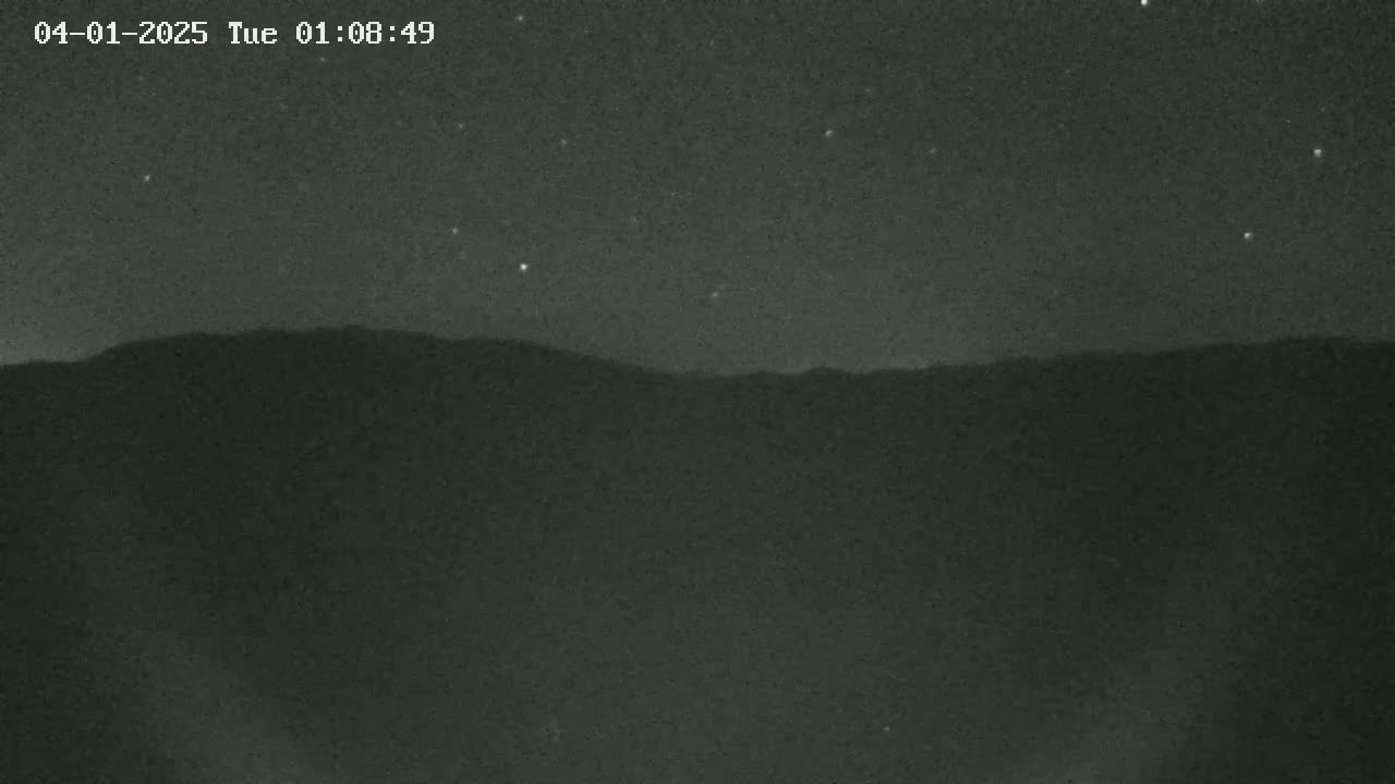 A nighttime long shot shows a dark mountain range under a clear, starry sky.