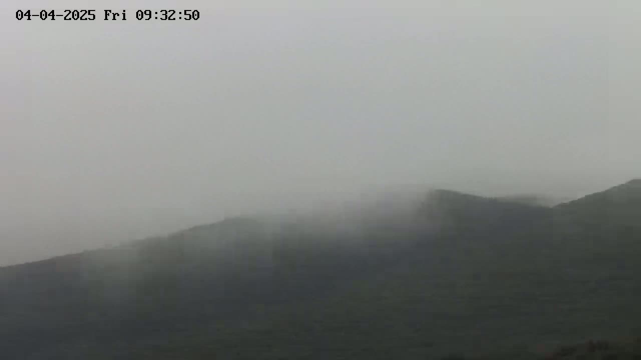 A foggy view of dark-colored hills is visible.