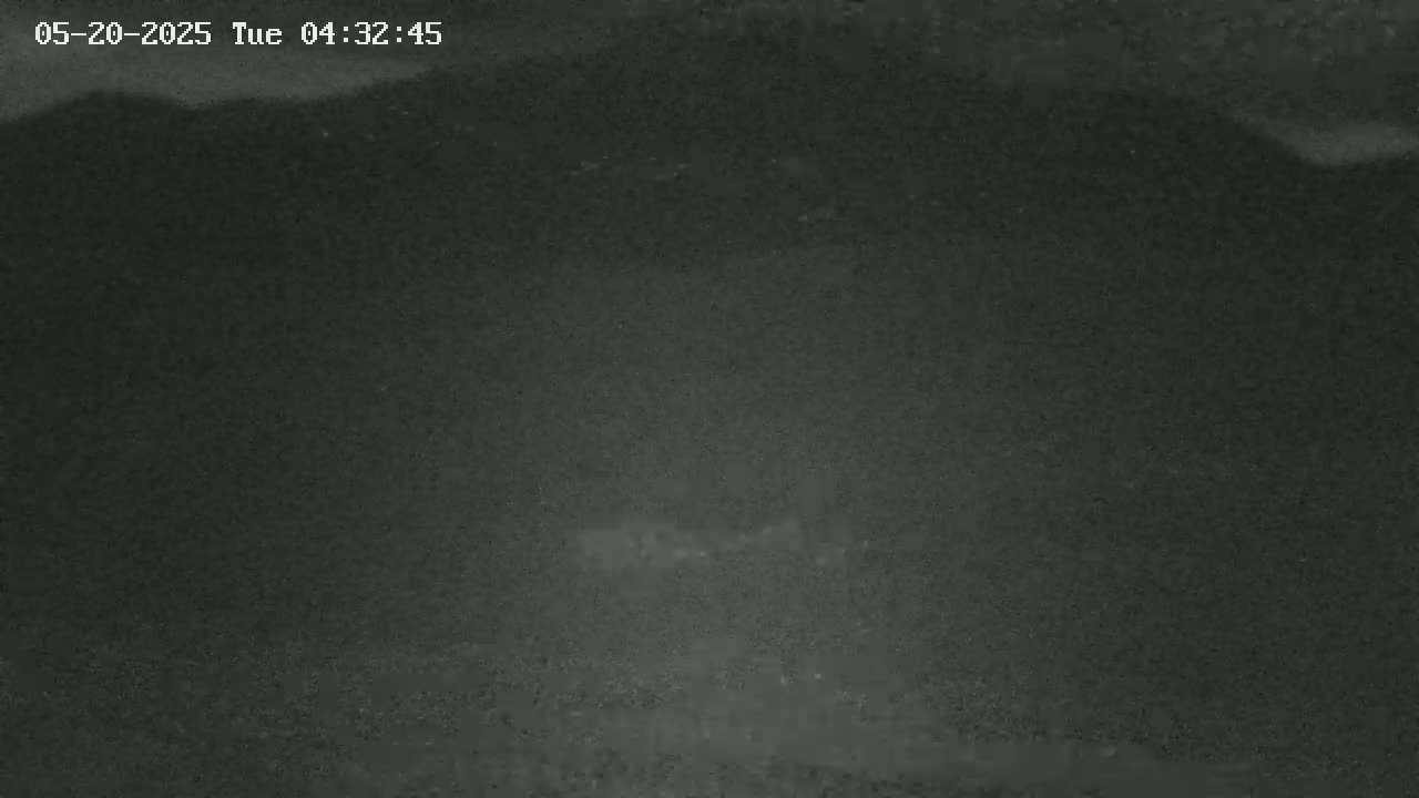 A dark, blurry nighttime image shows a mostly indistinct landscape under a clouded sky.