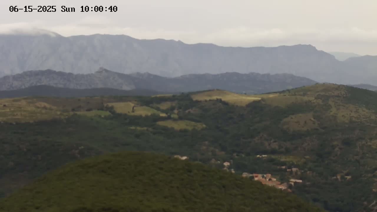 A distant view of rolling hills and mountains under a cloudy sky.