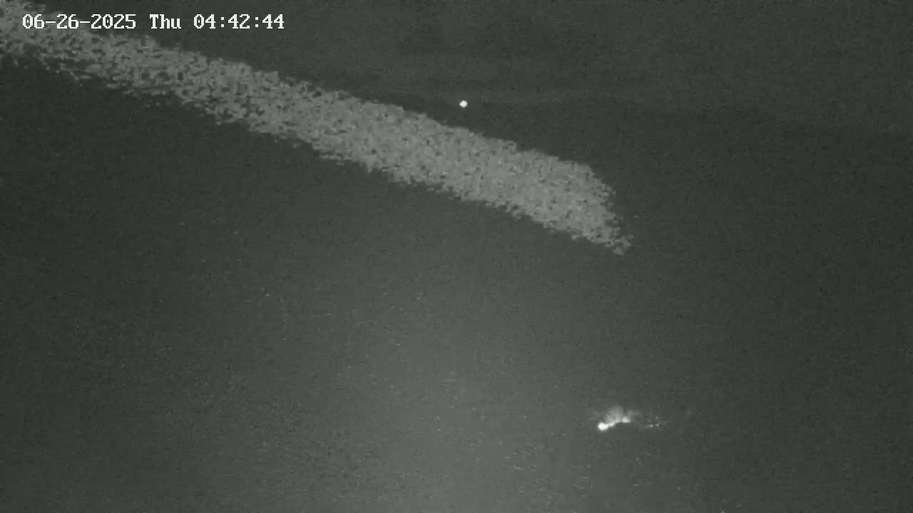 A nighttime, low-light image shows two bright streaks in the dark sky, one long and diffuse, the other short and more concentrated.