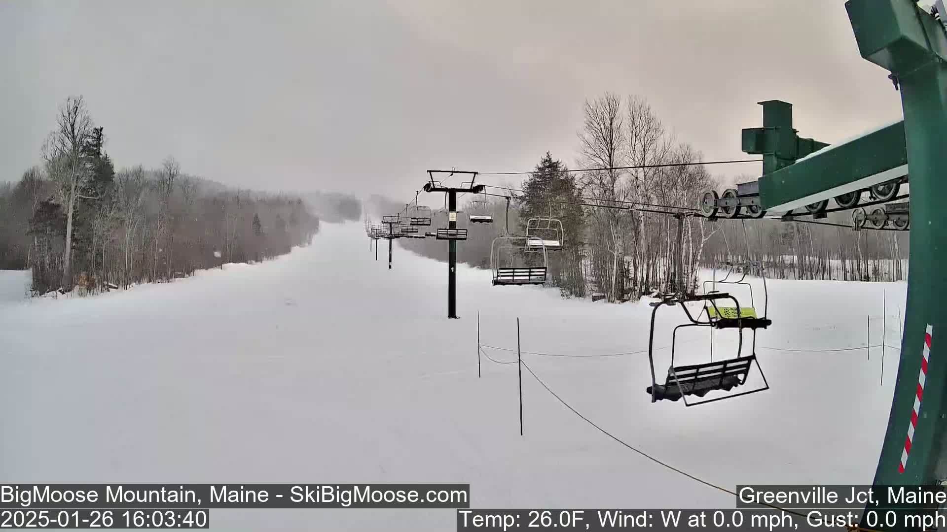 A snow-covered ski slope with a chairlift is visible under an overcast sky.