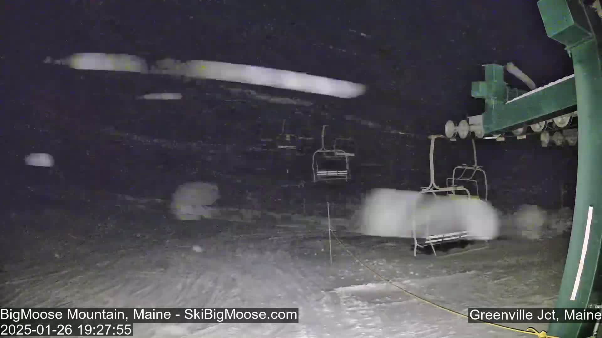 A nighttime view of a ski lift operating in heavy snowfall.