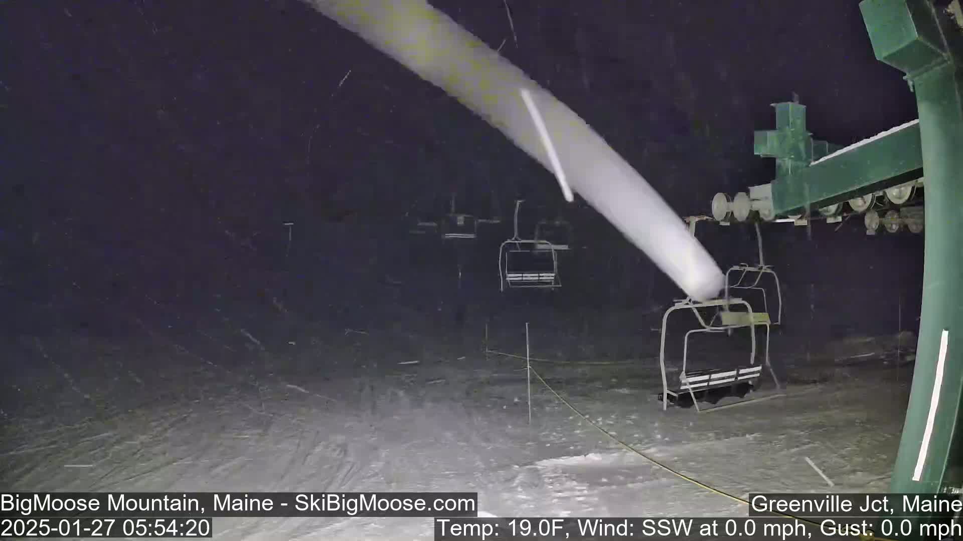 A nighttime view of a ski lift during a snowfall.