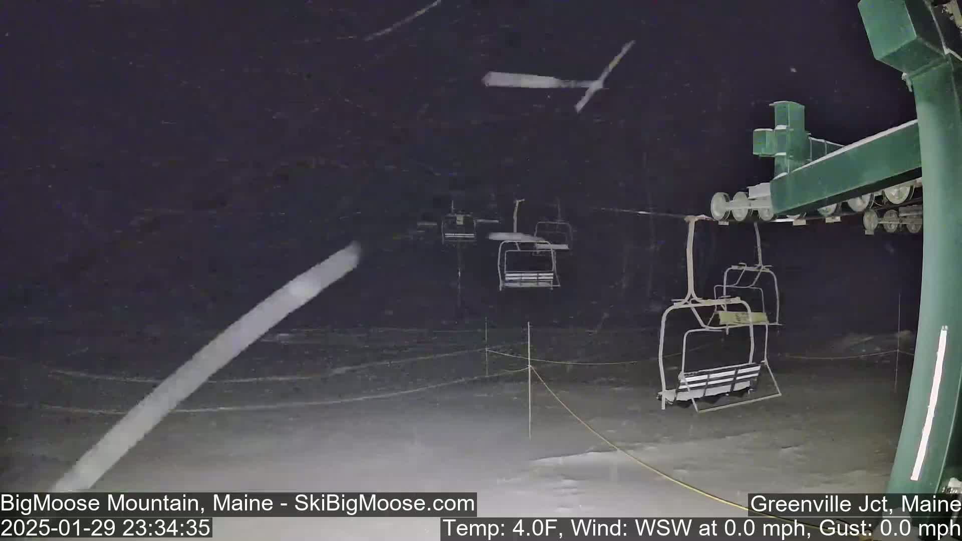 A ski lift at night under heavy snowfall.