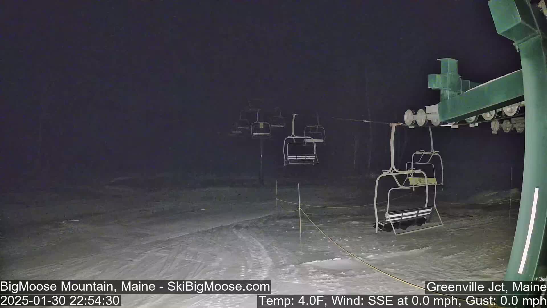 A nighttime view of a ski lift at a snow-covered resort, with calm, cold weather.
