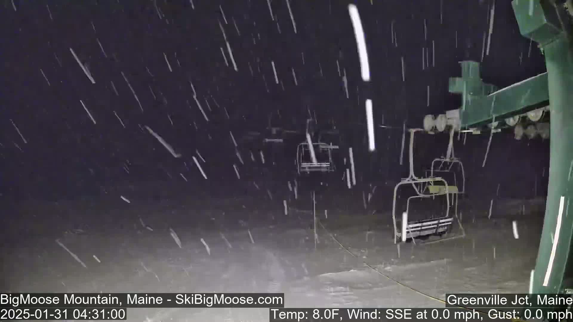 A nighttime view of a ski lift under heavy snowfall.