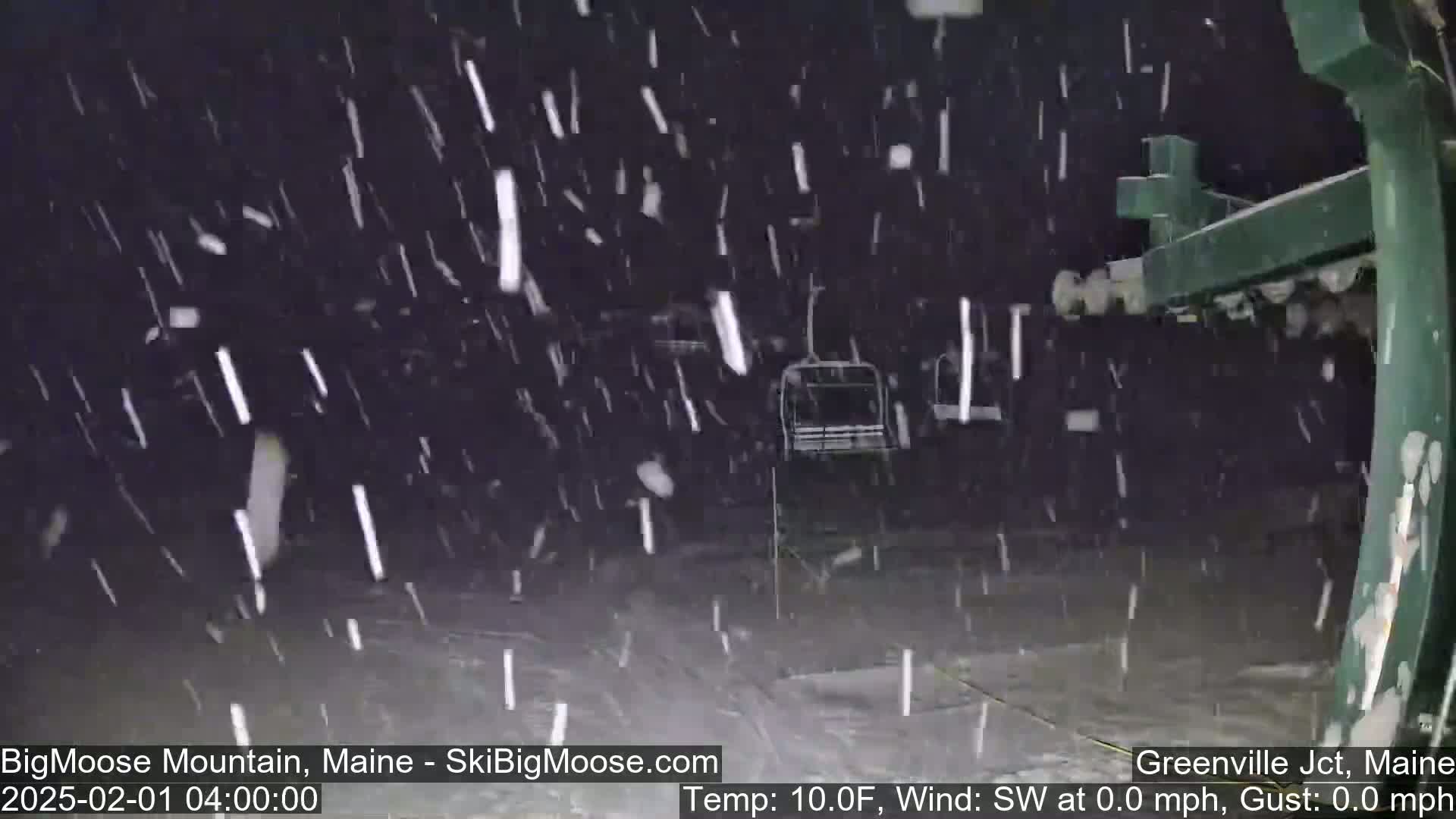 Snow falls heavily at night around a chairlift.
