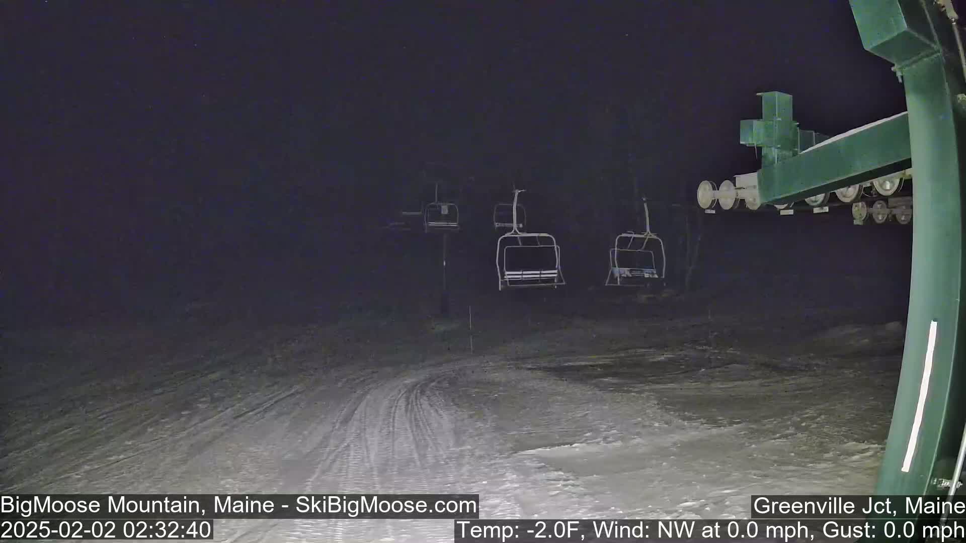 At night, a snow-covered ski slope is visible with several empty chairlifts under a clear, dark sky.