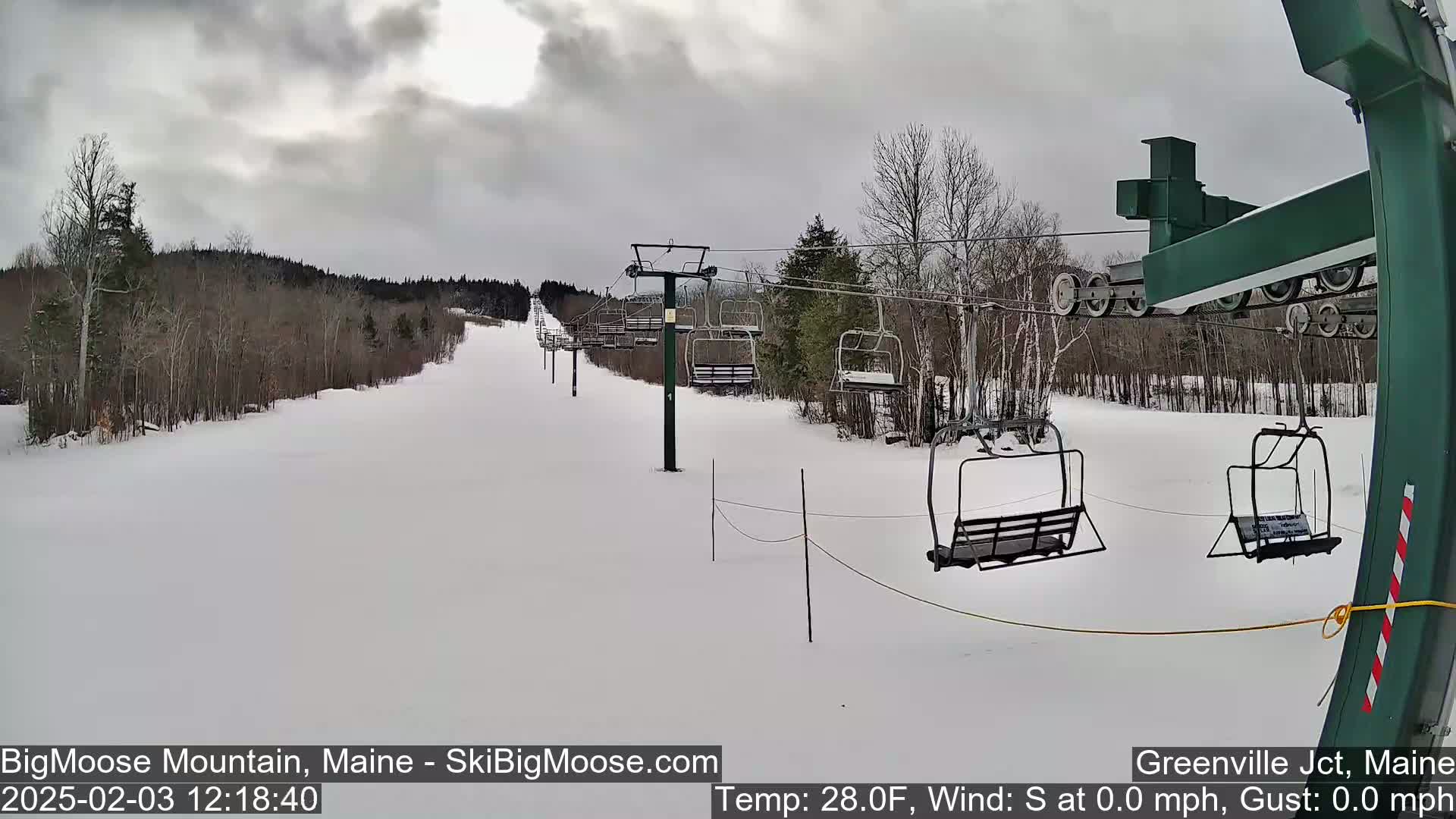 A snow-covered ski slope with a chairlift and overcast skies.