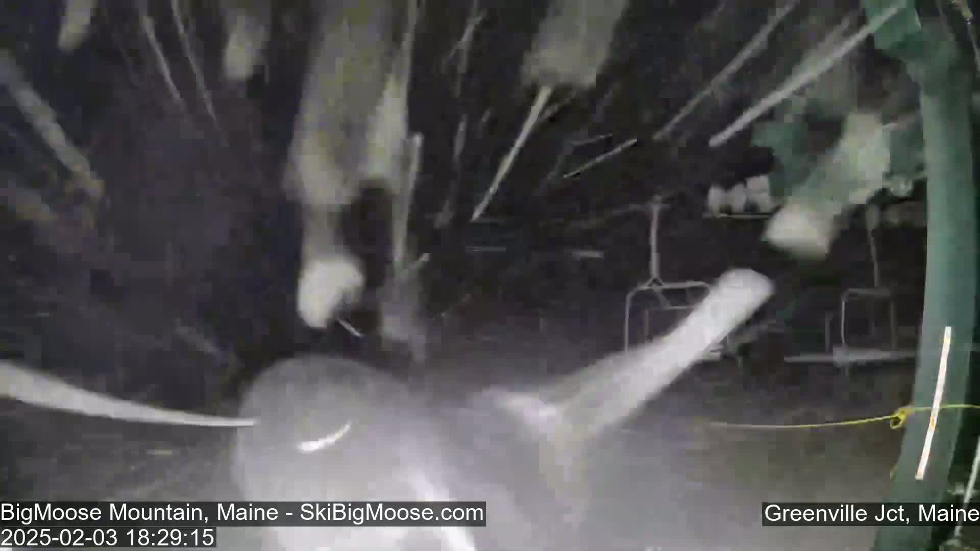 A nighttime scene of heavy snowfall obscuring a ski lift.