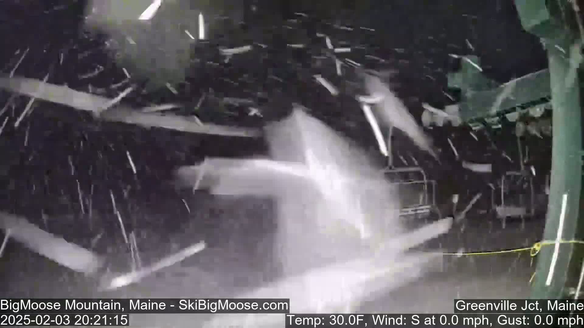 Snow is falling heavily on a dark, possibly industrial, outdoor scene filled with what appears to be a pile of broken or discarded materials.