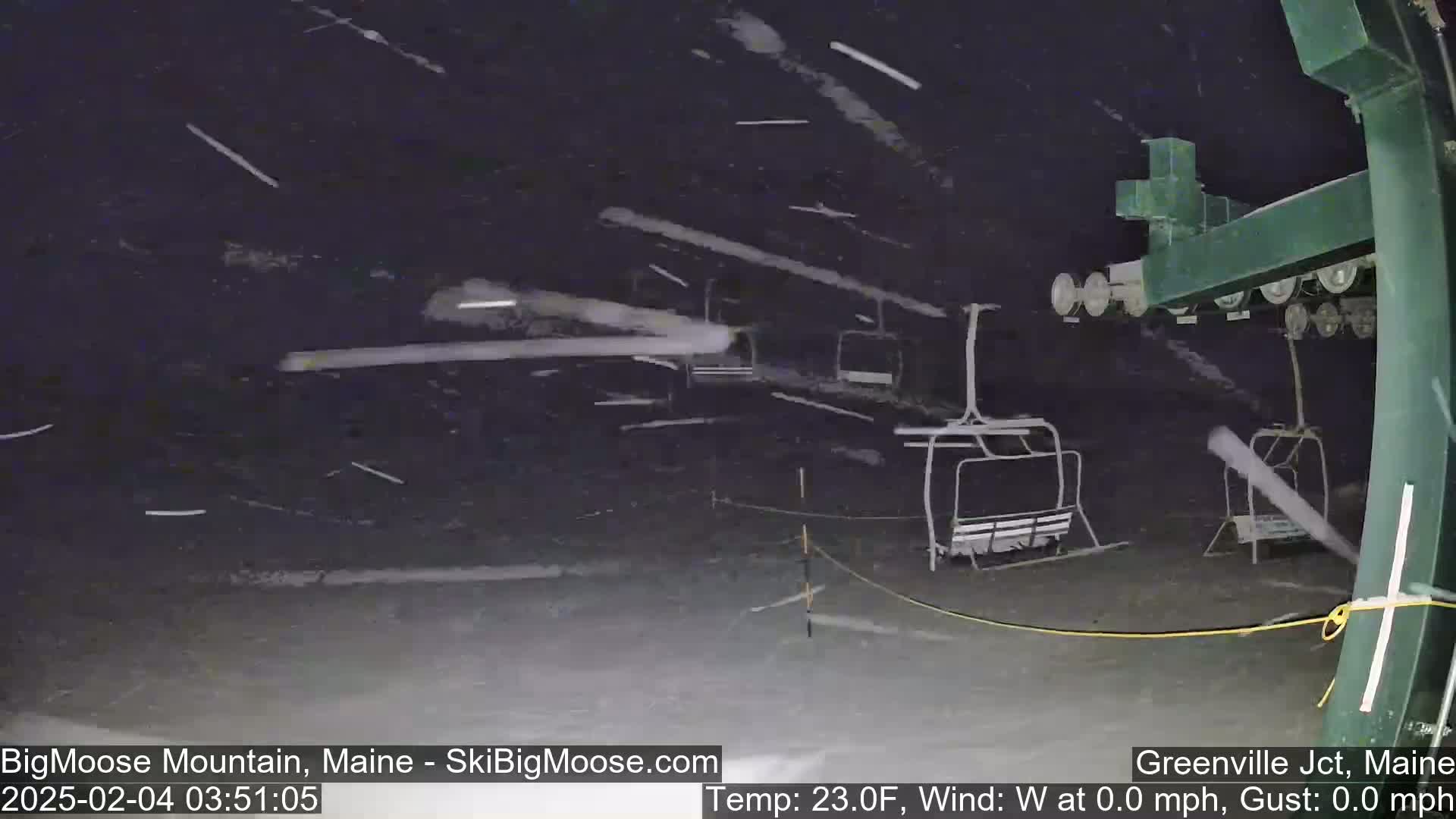 A nighttime scene of a ski lift during a heavy snowfall with calm winds.