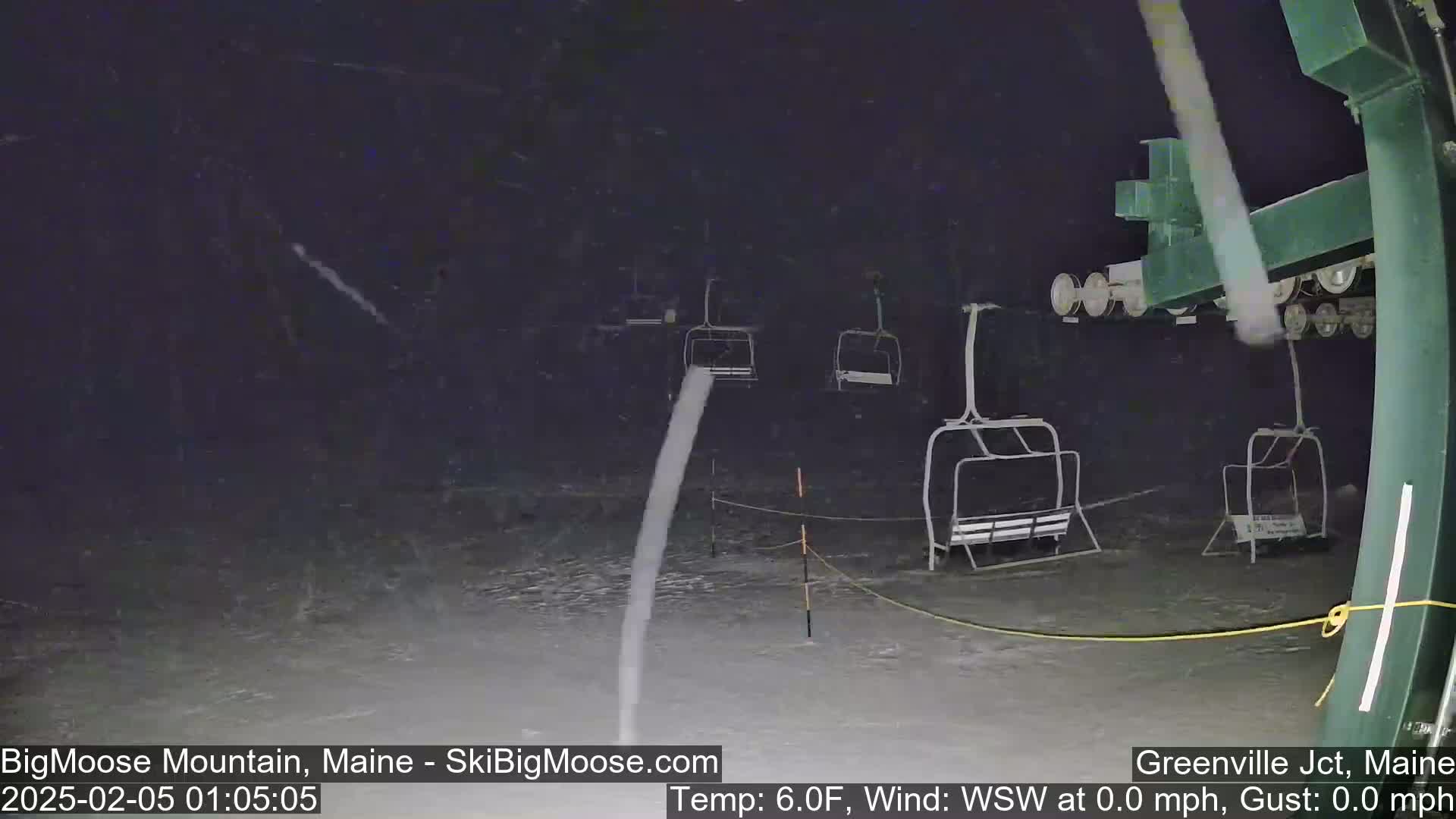 A nighttime view of a ski lift in heavy snowfall.