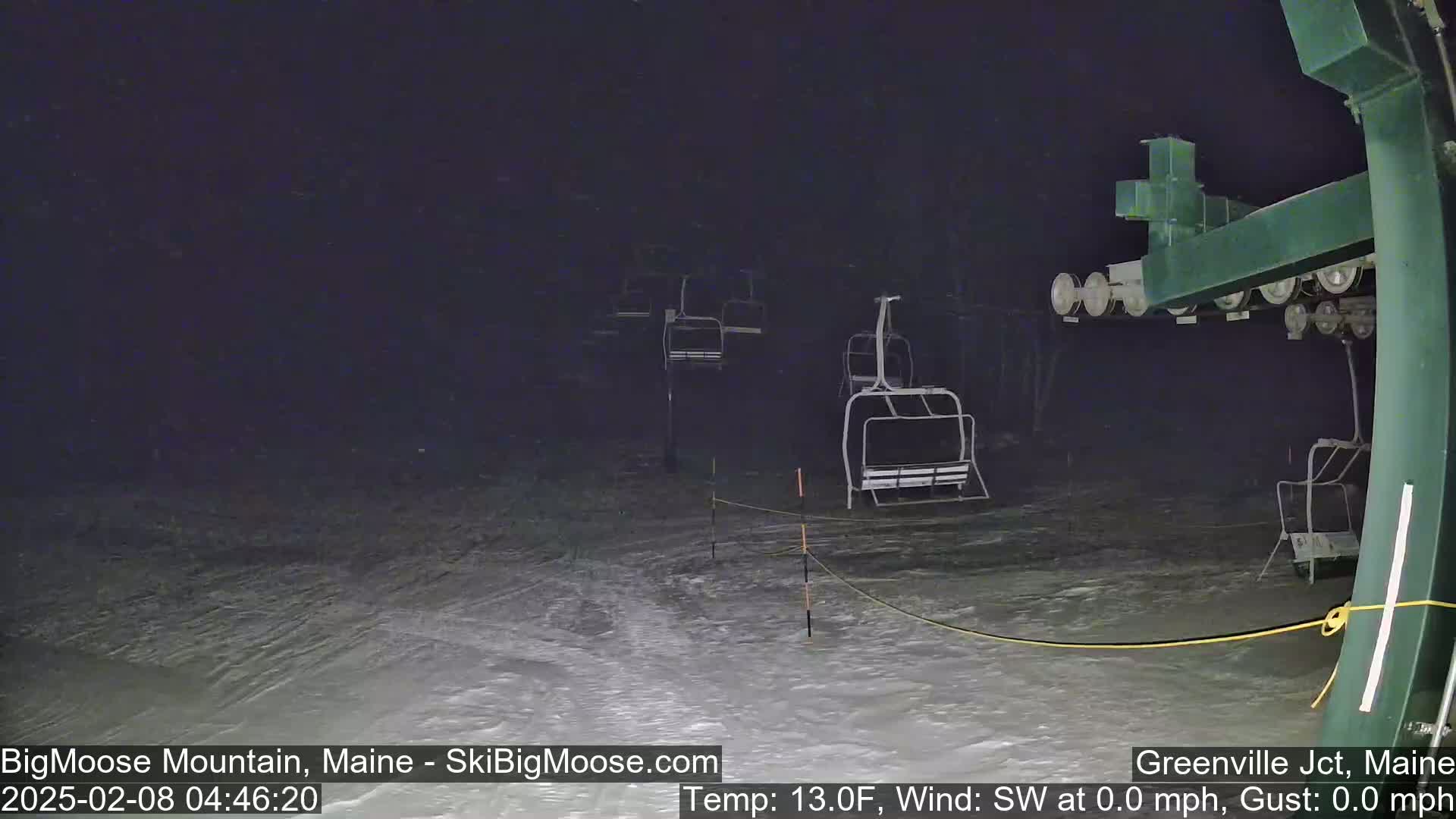 Several empty chairlifts are visible at night in snowy conditions.