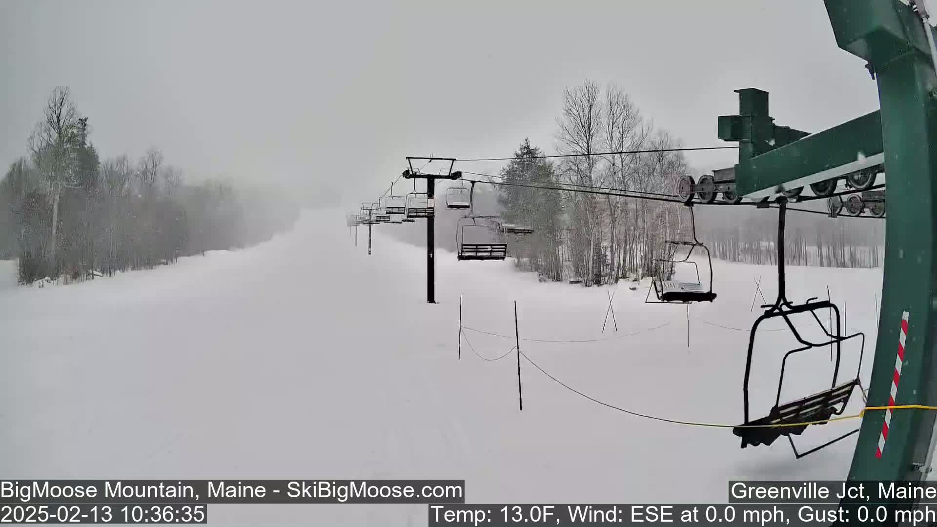 A snow-covered ski slope with a chairlift is visible during a heavy snowstorm.