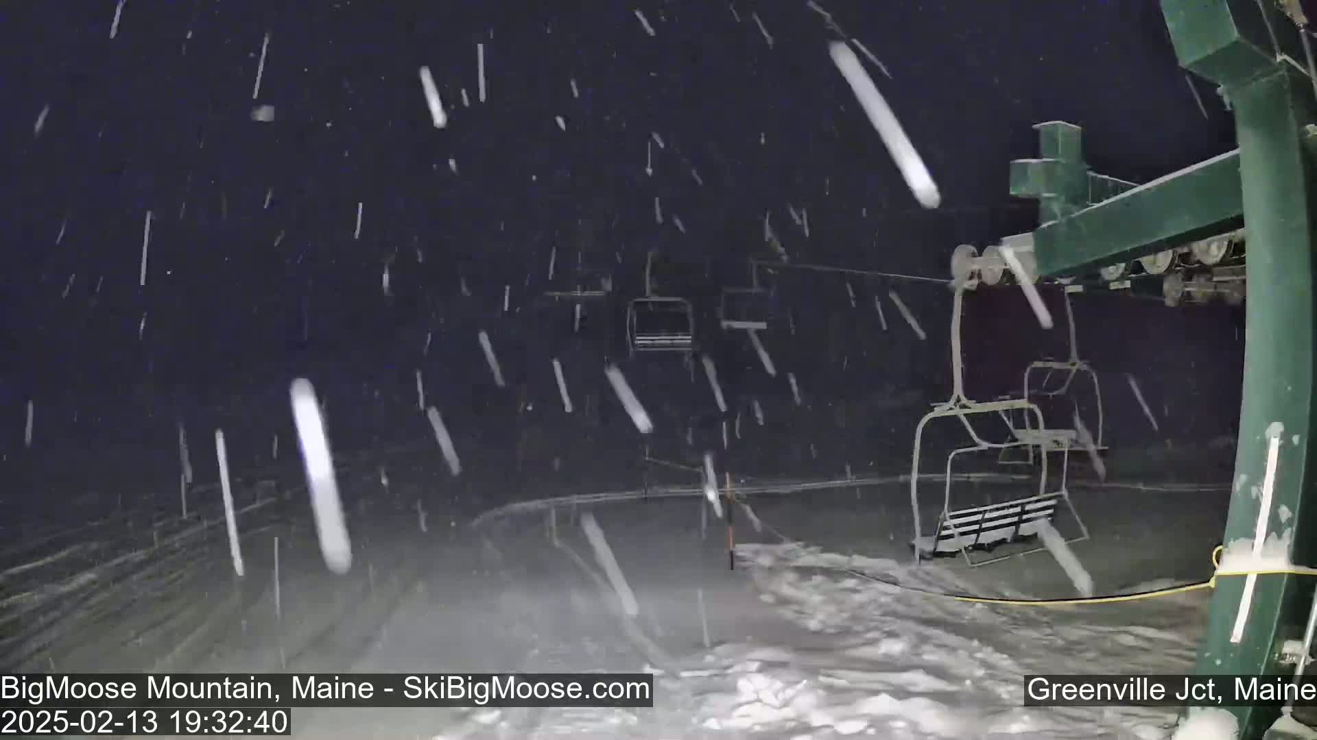 A ski lift is shown at night during a heavy snowfall.