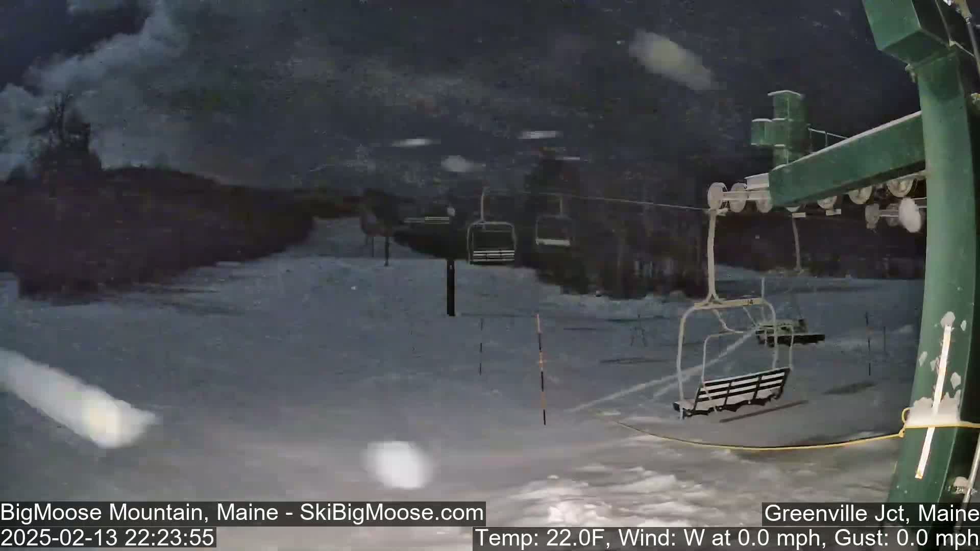 A nighttime snowstorm blankets a ski lift and snowy terrain.