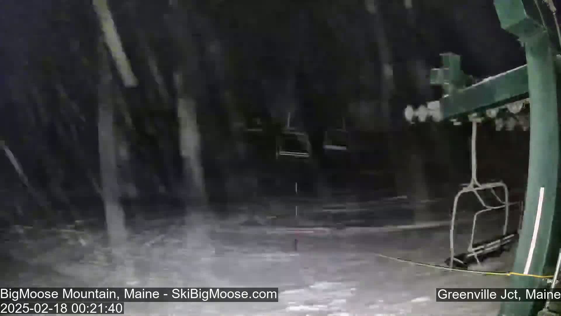 A nighttime view of a snow-covered ski lift during a heavy snowfall.