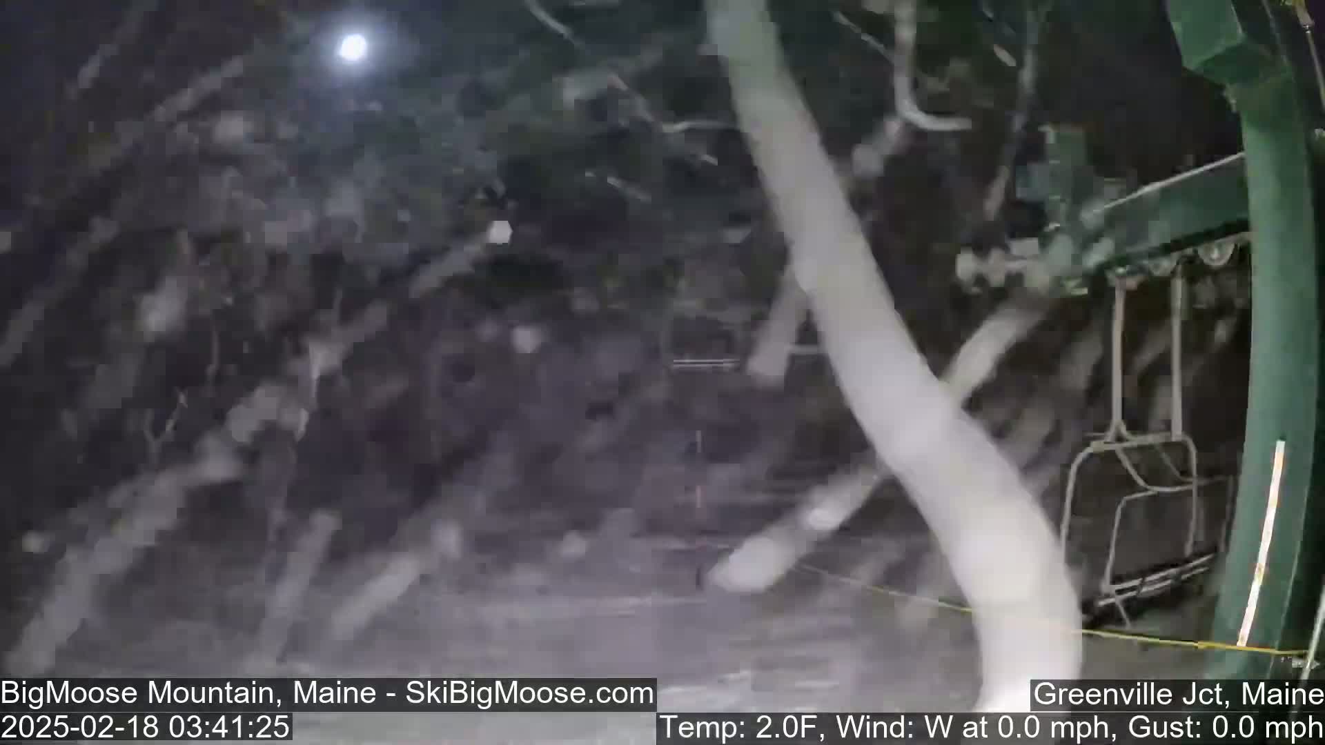 A nighttime view of a snow-covered ski lift during a heavy snowfall.