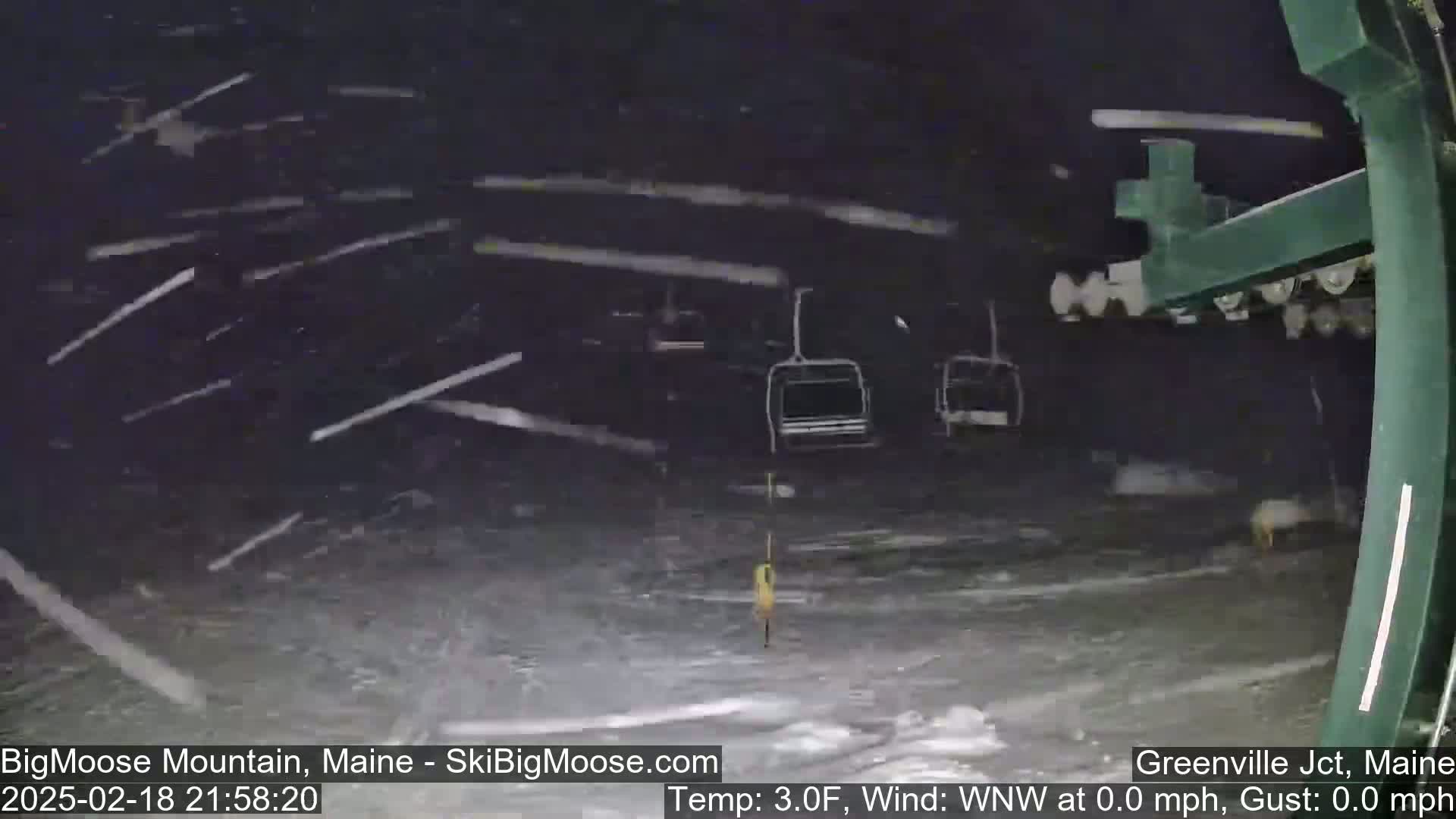 A nighttime view of a ski lift under heavy snowfall.